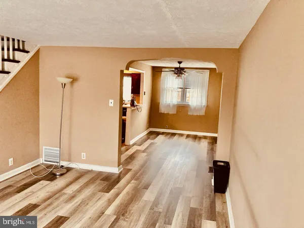 a view of a hallway with wooden floor and a bathroom