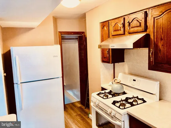 a kitchen with stainless steel appliances granite countertop a refrigerator a stove and a sink with wooden floor