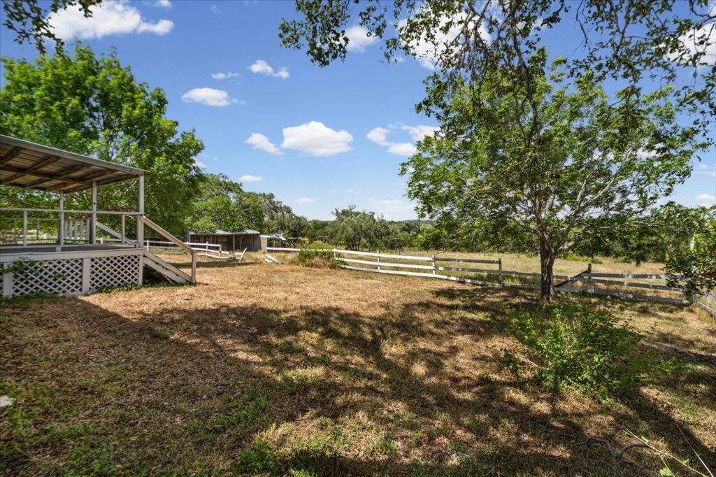 13501 Nutty Brown Road, Unit B Austin, TX 78737 - Photo 22 of 29 A spacious backyard with mature trees, verdant landscaping, and white fencing, providing a tranquil outdoor setting.