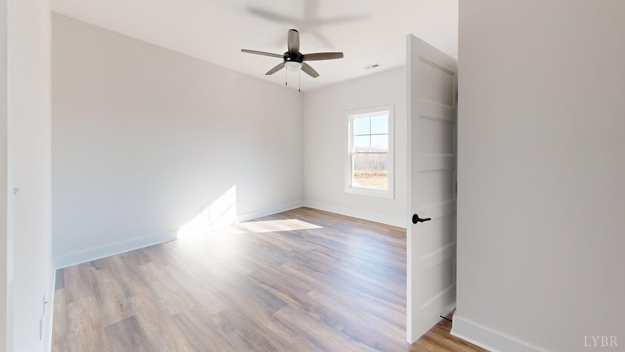 1868 Skinnell Mill Road Bedford, VA 24523 - Photo 11 of 24 an empty room with wooden floor ceiling fan and windows