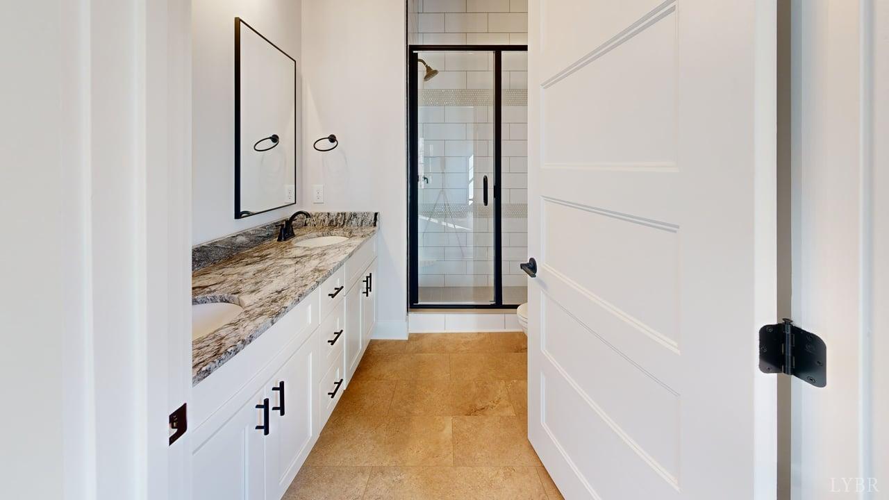 1868 Skinnell Mill Road Bedford, VA 24523 - Photo 14 of 24 a bathroom with a double vanity sink a toilet a glass door and shower
