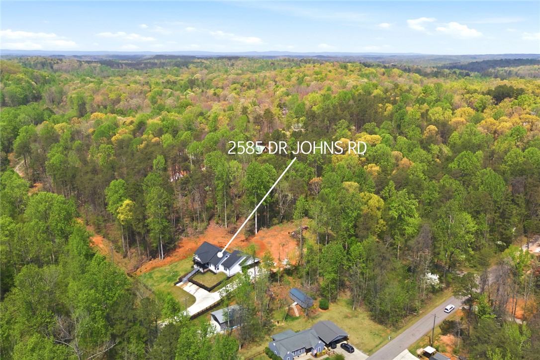 2585 Dr Johns Road Westminster, SC 29693 - Photo 38 of 40 An aerial view showcases a residential property surrounded by expansive natural woodlands and a clear sky.