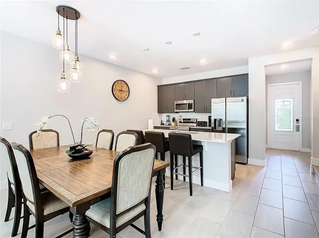 a kitchen with granite countertop a table chairs a sink dishwasher refrigerator and cabinets