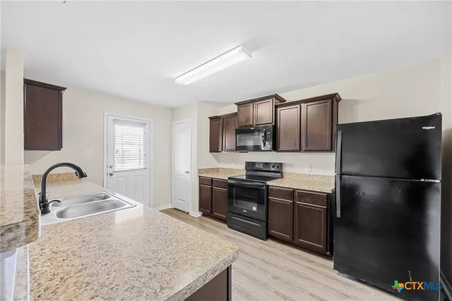 a kitchen with granite countertop a refrigerator and a sink