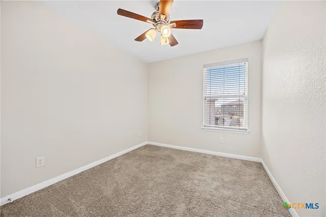 an empty room with a window and a fan