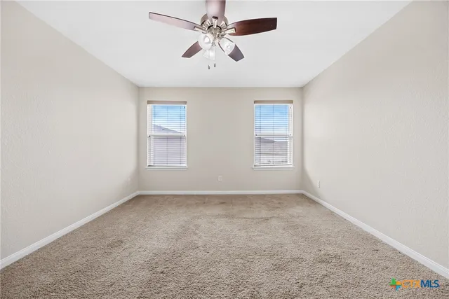 an empty room with windows and fan