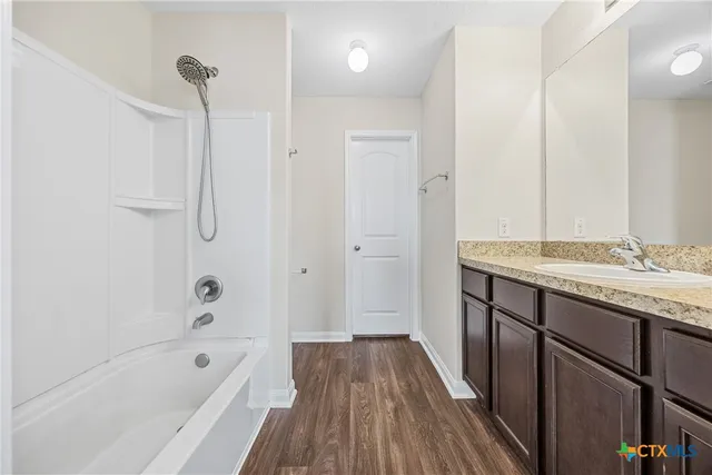 a bathroom with a tub a sink a vanity and a shower