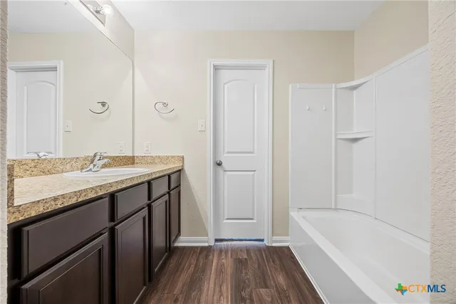 a bathroom with a tub a sink and a large mirror