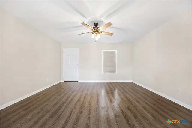 a view of a room with wooden floor and a ceiling fan