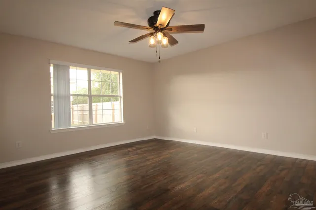 a view of an empty room with window and wooden floor