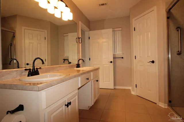 a spacious bathroom with a double vanity sink a mirror and shower