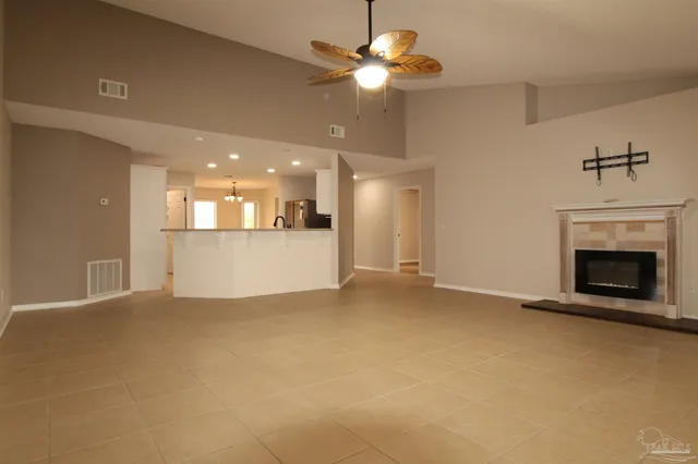 a view of a livingroom with a fireplace a ceiling fan and kitchen view