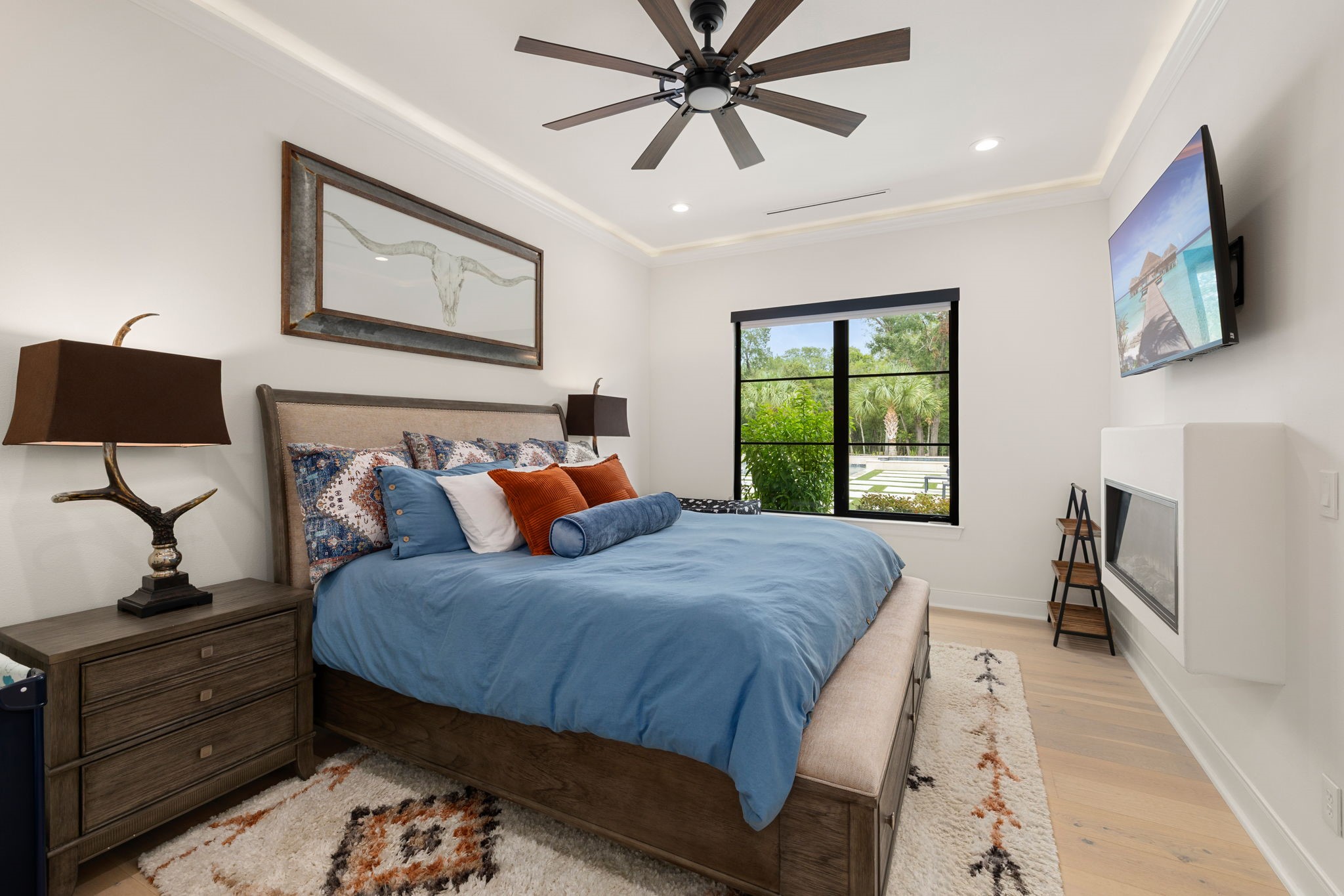 1100 Felder Road Washington, TX 77880 - Photo 32 of 50 This secondary bedroom offers a comfortable retreat with a built-in LED fireplace and large windows framing views of the pool and grounds beyond.