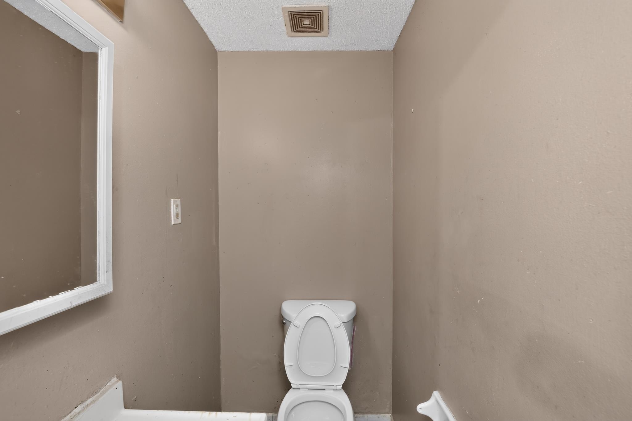 3791 Windermere Road Memphis, TN 38128 - Photo 15 of 18 Compact bathroom featuring a white toilet, framed mirror, and beige wall paint