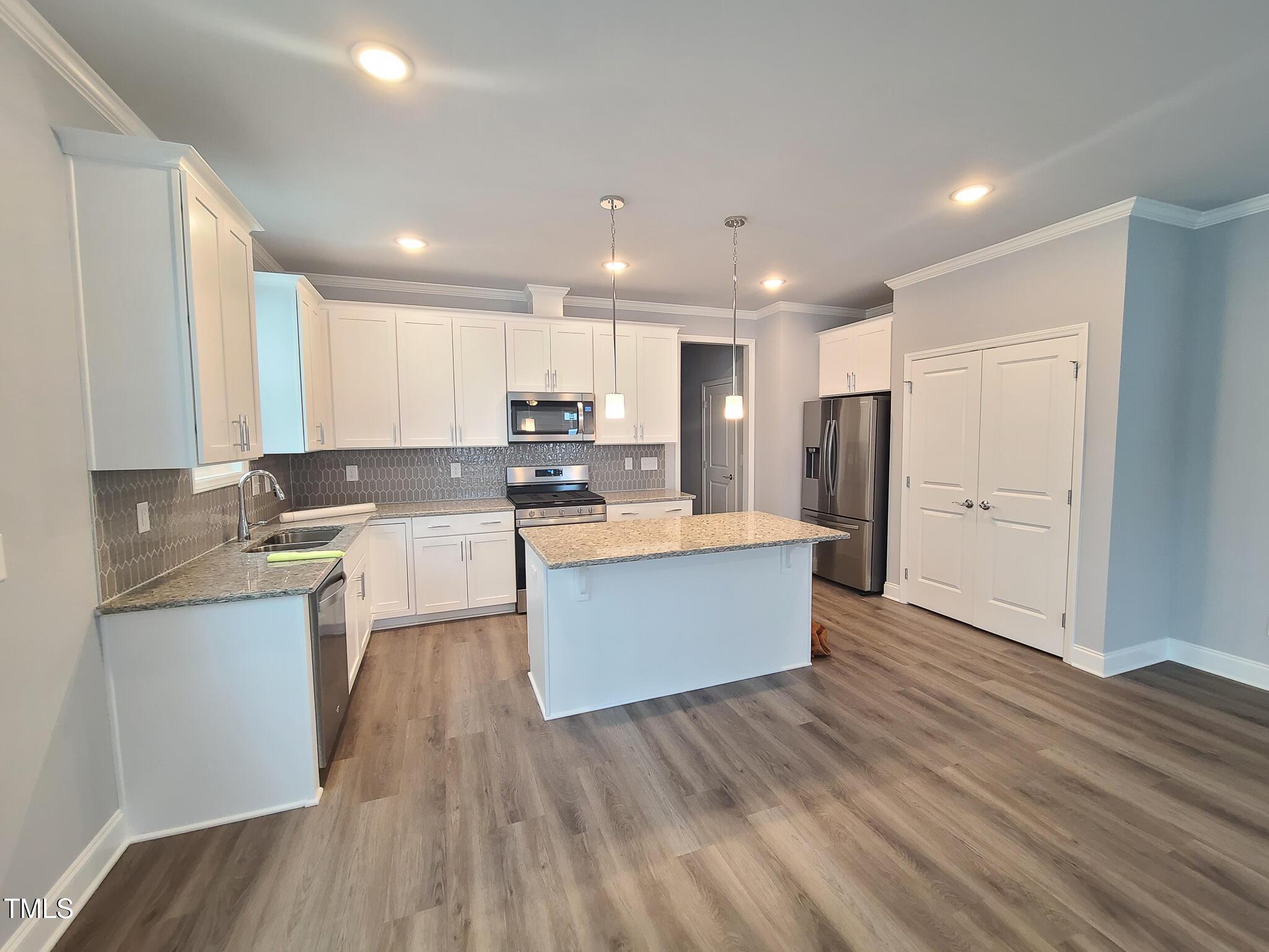 1629 Glazebrook Drive Wake Forest, NC 27587 - Photo 8 of 35 a large kitchen with stainless steel appliances kitchen island a sink dishwasher a refrigerator and white cabinets with wooden floor