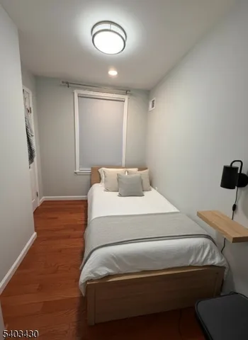 a bedroom with a bed and a lamp with the wooden floor