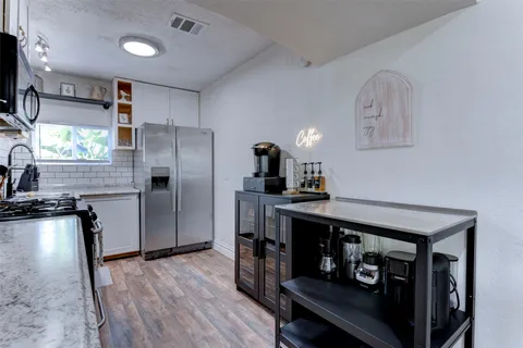 a kitchen with a refrigerator a sink dishwasher a stove and a dining table with wooden floor