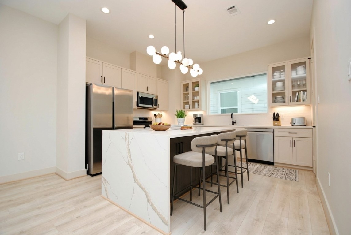 6310 Illinois Street, Unit A Houston, TX 77021 - Photo 6 of 22 a kitchen with a refrigerator a sink dishwasher a dining table and chairs with wooden floor