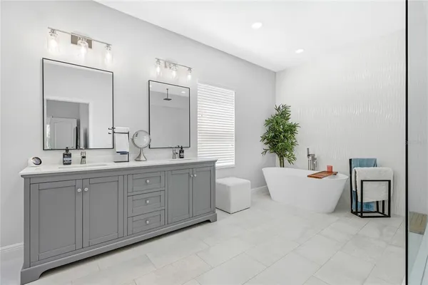 a bathroom with a white tub a sink and mirror