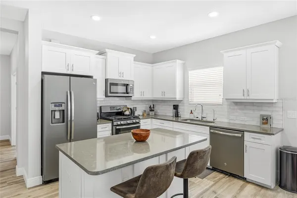 a kitchen with stainless steel appliances granite countertop a sink a stove a refrigerator cabinets and a center island