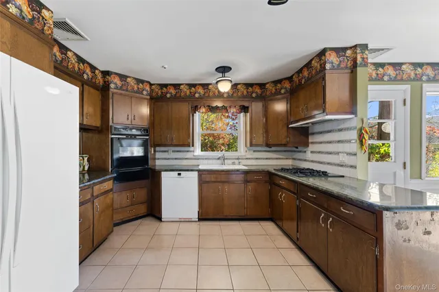 a kitchen with stainless steel appliances granite countertop a sink and dishwasher a refrigerator with wooden cabinets