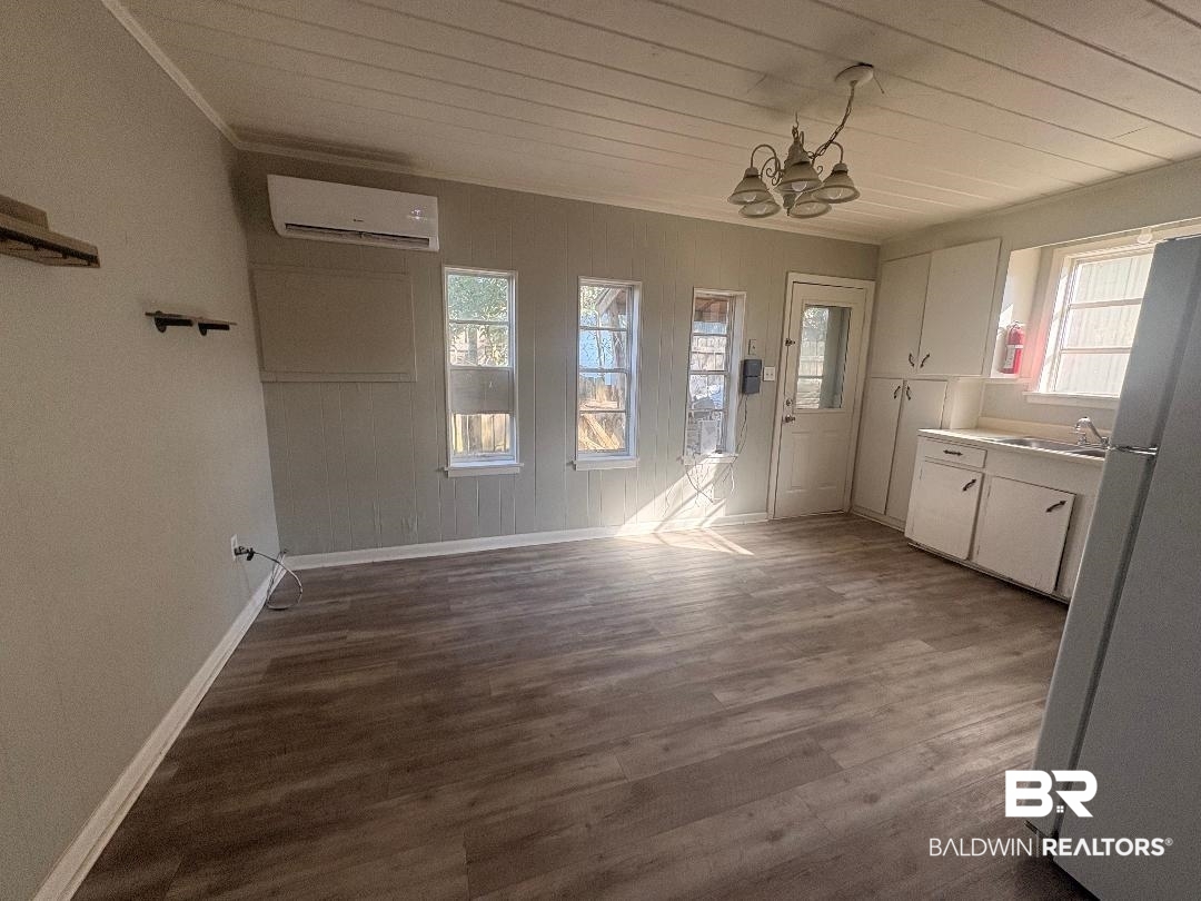 9330 Pinewood Avenue, Unit S 1 2 3 4 Elberta, AL 36530 - Photo 6 of 12 Unfurnished dining area featuring suspended lighting, dark wood-style floors, and ornamental molding