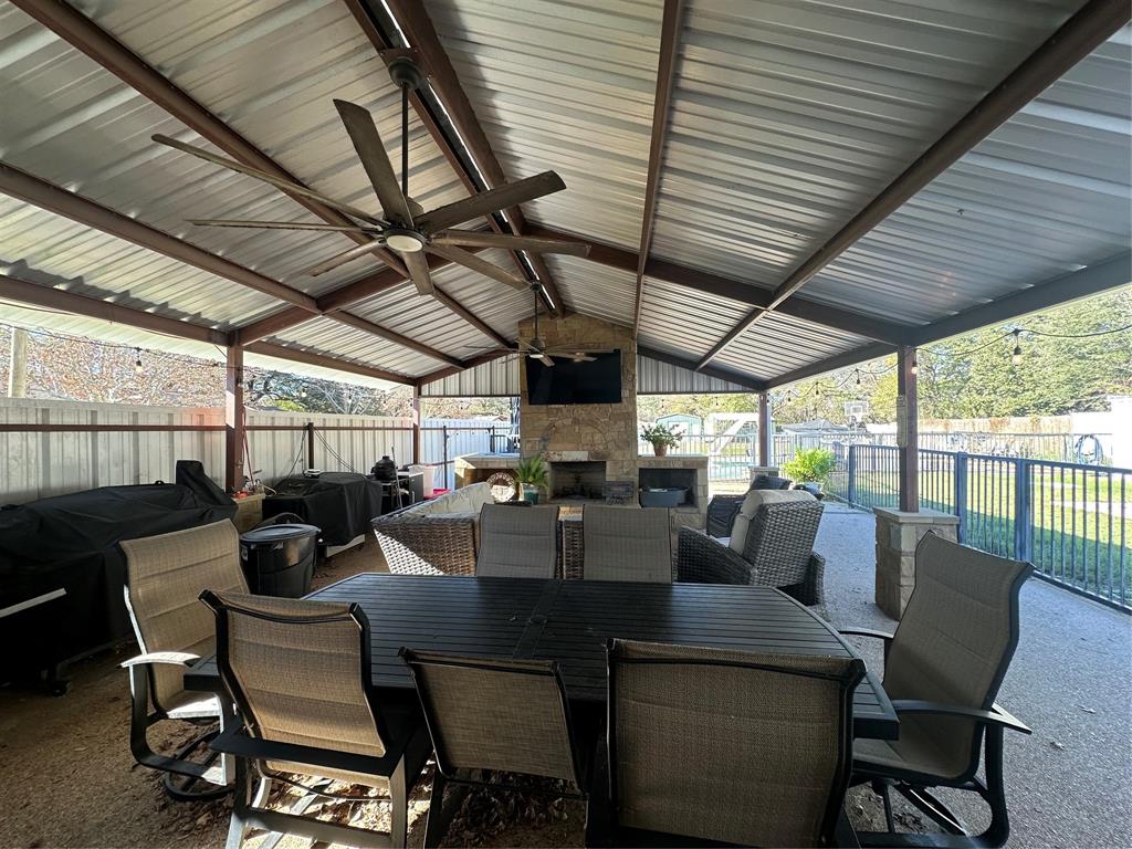 101 Twin Creek Road Comanche, TX 76442 - Photo 9 of 28 Fenced backyard featuring ceiling fan, outdoor dining area, an outdoor stone fireplace, and a patio area