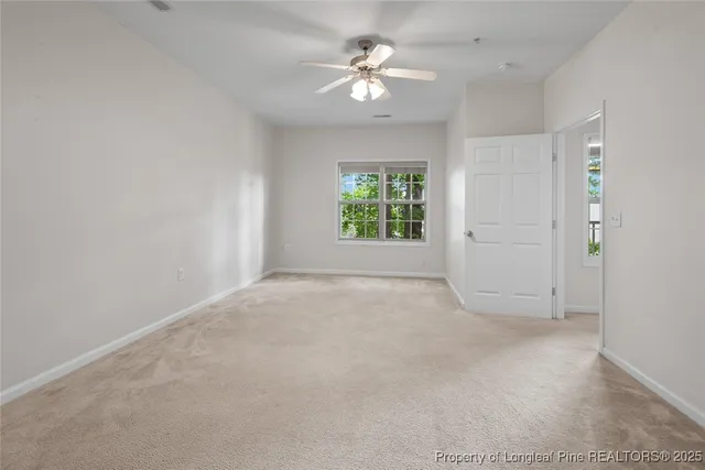 an empty room with windows and ceiling fan