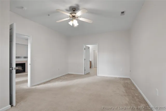 an empty room with a chandelier fan and windows