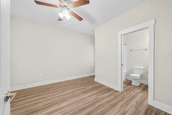 an empty room with wooden floor ceiling fan and windows