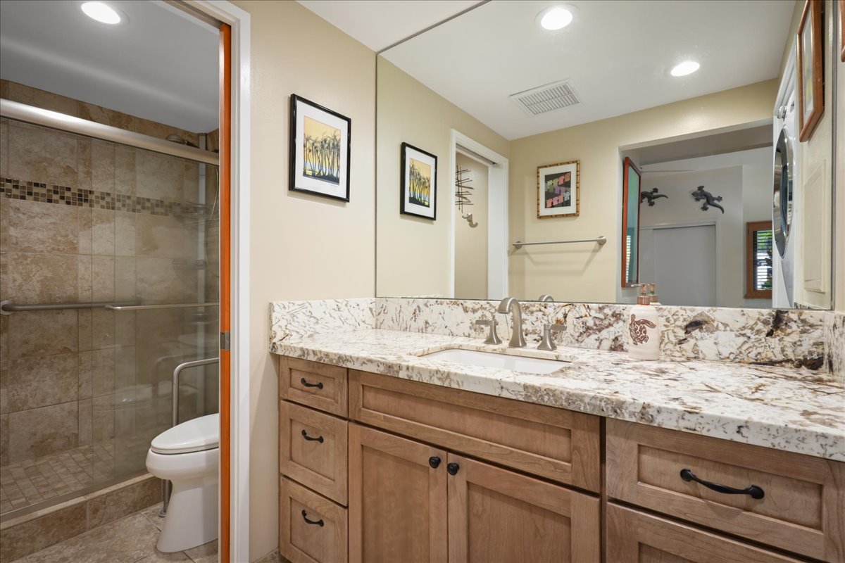 75-6040 Alii Drive, Unit 303 Kailua-Kona, HI 96740 - Photo 18 of 24 a bathroom with a granite countertop toilet sink and a mirror