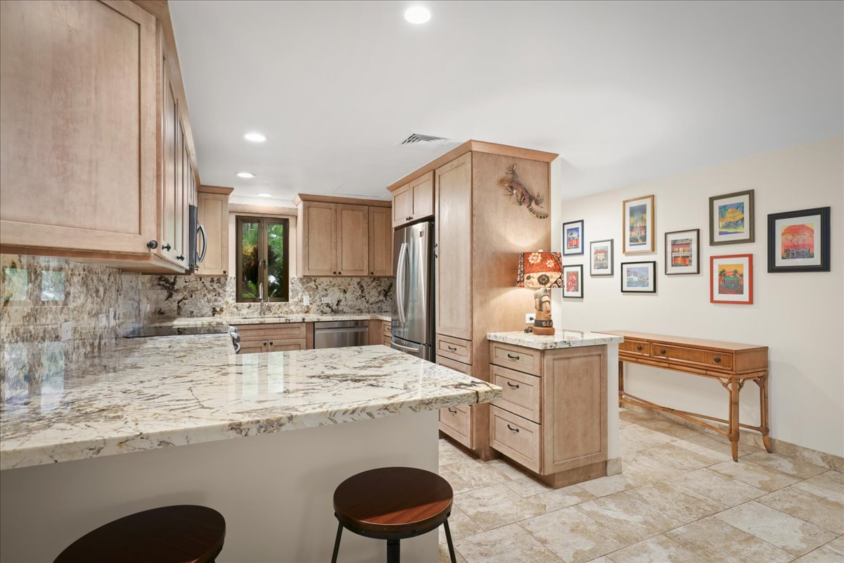 75-6040 Alii Drive, Unit 303 Kailua-Kona, HI 96740 - Photo 3 of 24 a kitchen with stainless steel appliances granite countertop a sink stove and refrigerator