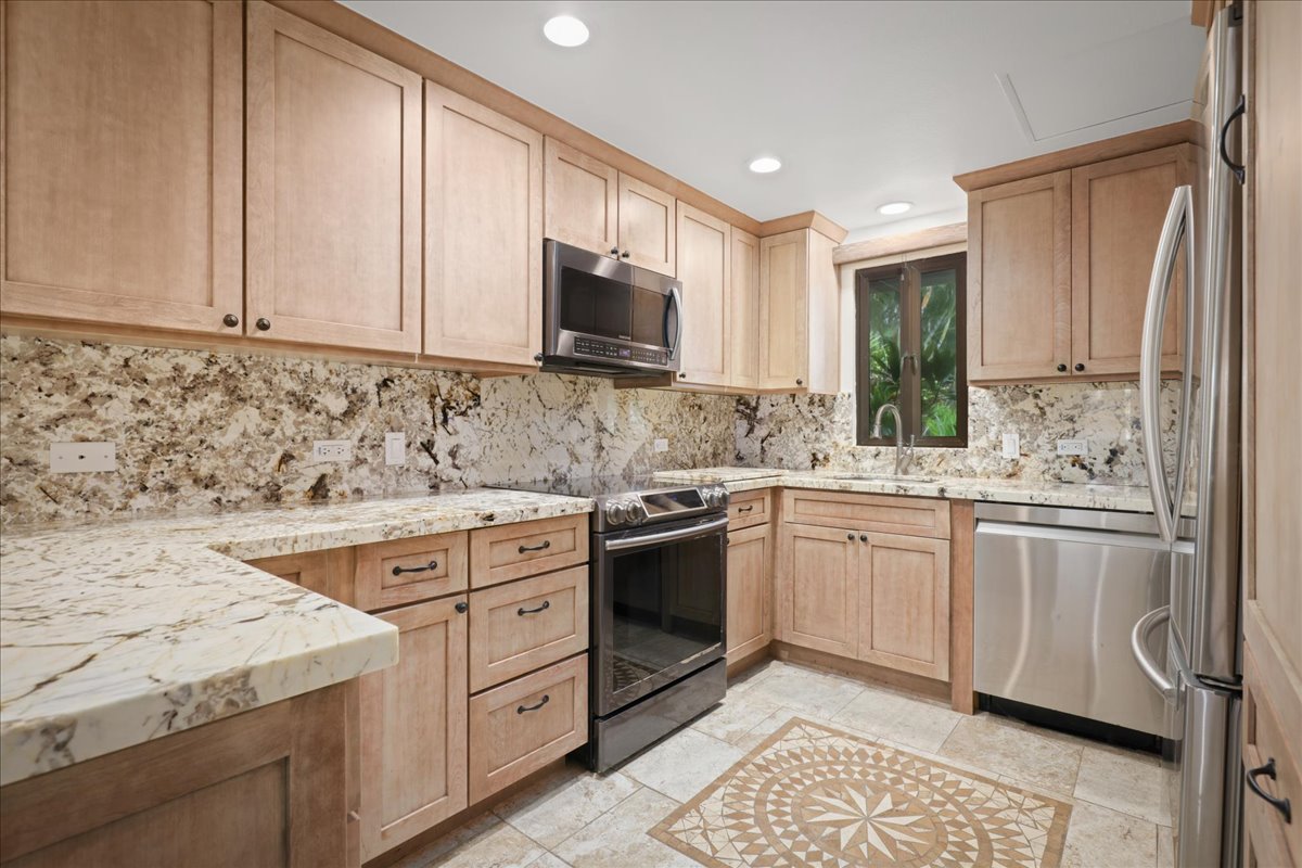 75-6040 Alii Drive, Unit 303 Kailua-Kona, HI 96740 - Photo 8 of 24 a kitchen with granite countertop cabinets stainless steel appliances and a sink