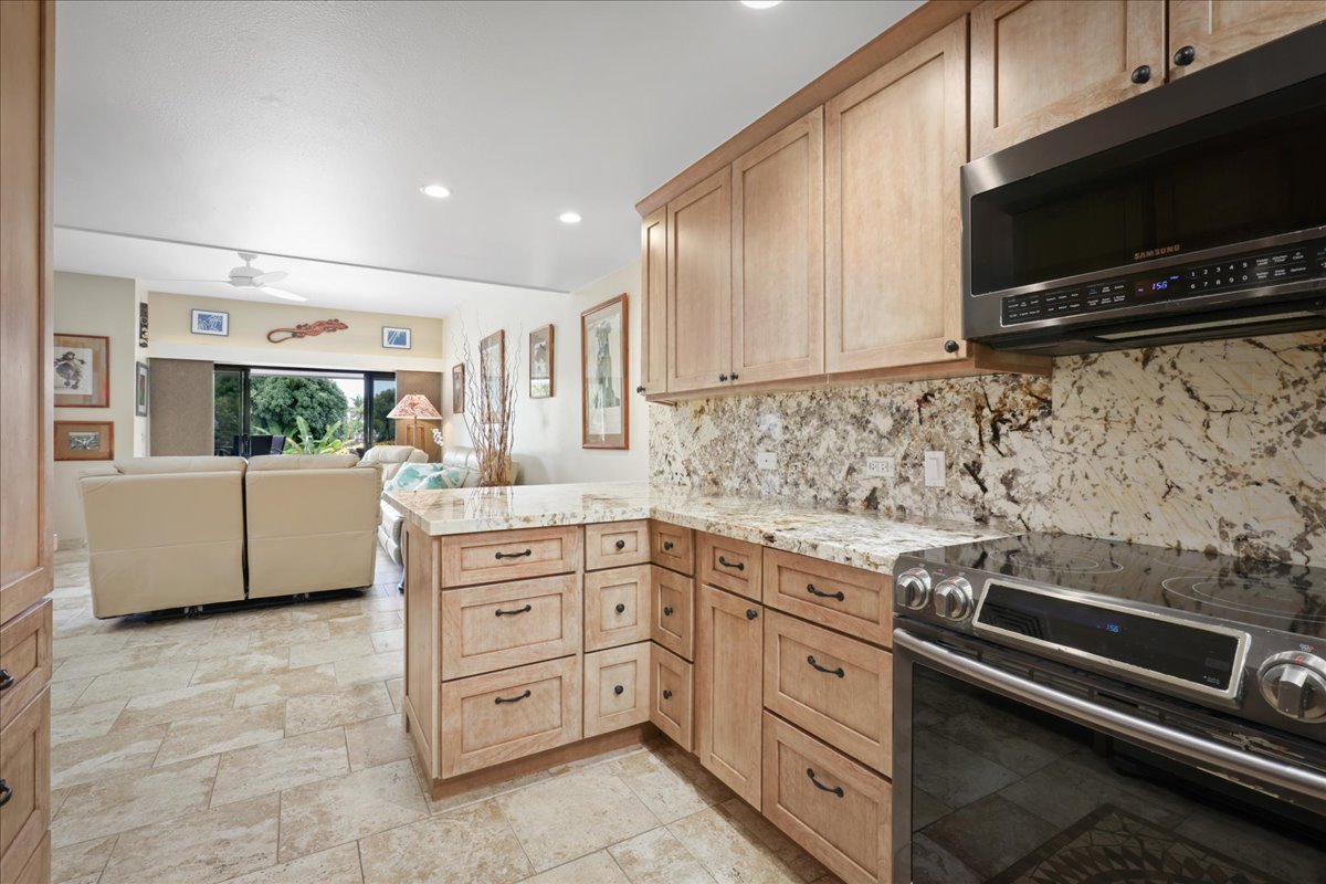 75-6040 Alii Drive, Unit 303 Kailua-Kona, HI 96740 - Photo 9 of 24 a kitchen with stainless steel appliances and cabinets