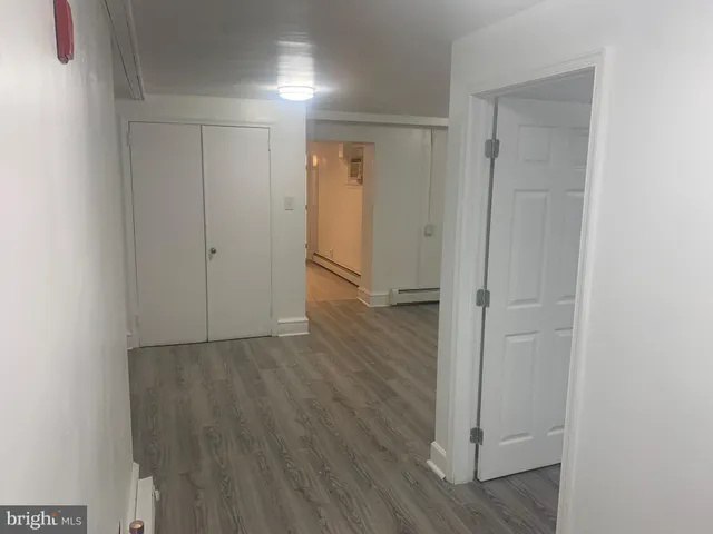 a view of an empty room with wooden floor and a hallway
