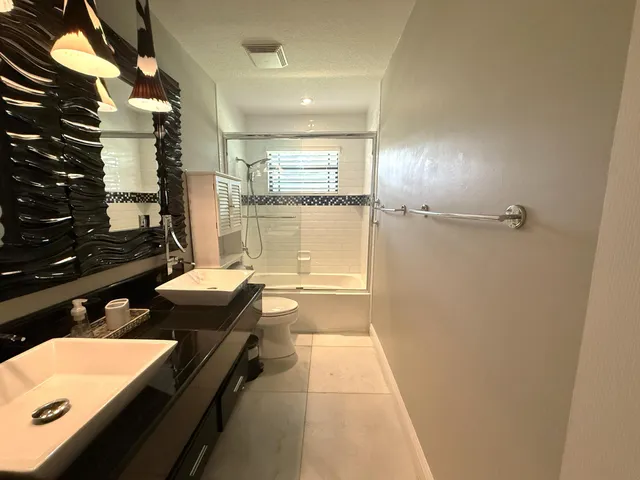 a bathroom with a granite countertop sink a toilet and shower