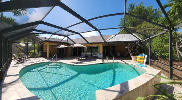 a view of a backyard with swimming pool and sitting area