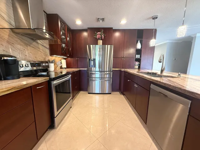 a kitchen with stainless steel appliances granite countertop a sink a stove and a refrigerator
