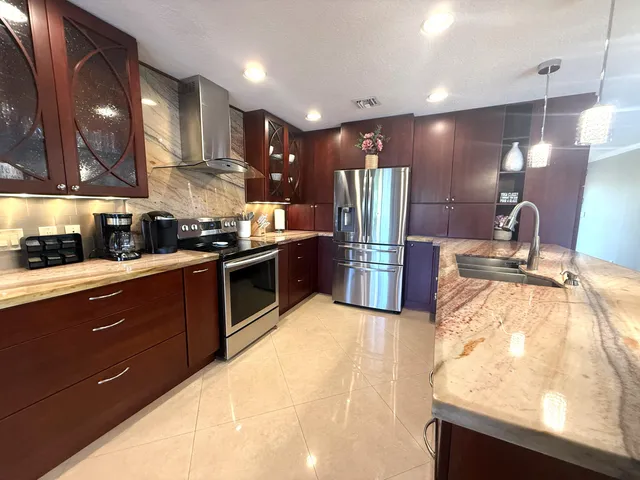 a kitchen with stainless steel appliances kitchen island granite countertop a refrigerator and a stove top oven