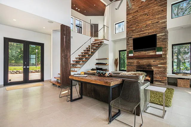 a living room with furniture floor to ceiling windows and a dining table