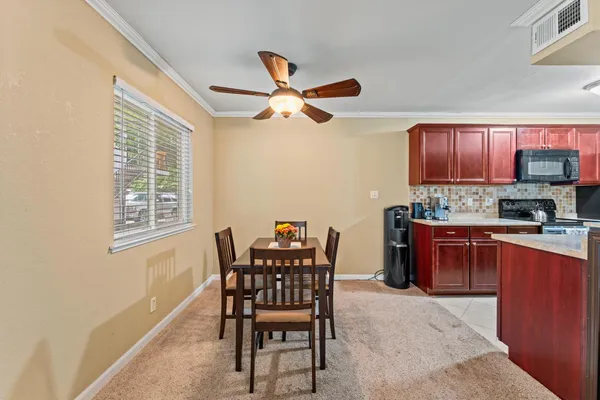 a kitchen with stainless steel appliances granite countertop a stove top oven a sink a dining table and chairs