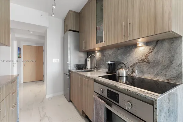 a kitchen with stainless steel appliances granite countertop a sink and a refrigerator