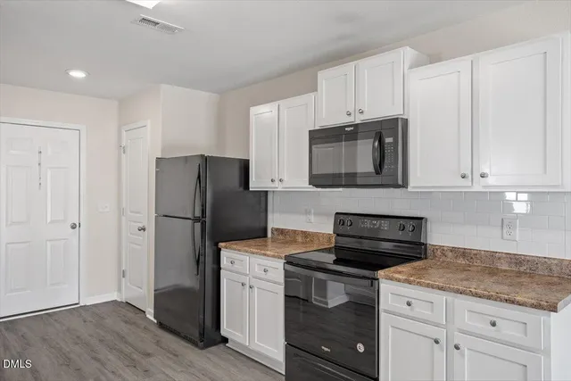 a kitchen with granite countertop white cabinets and stainless steel appliances