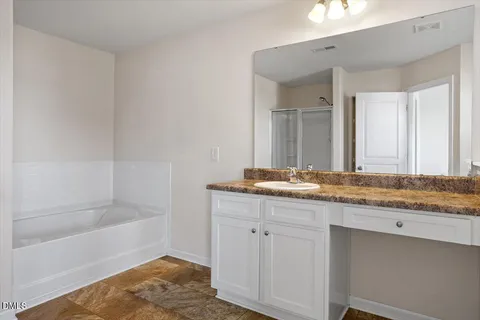 a bathroom with a granite countertop sink a mirror and a bathtub