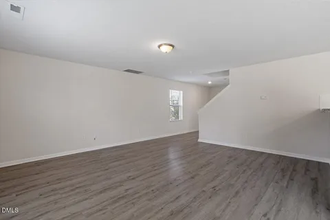a view of an empty room with wooden floor and window