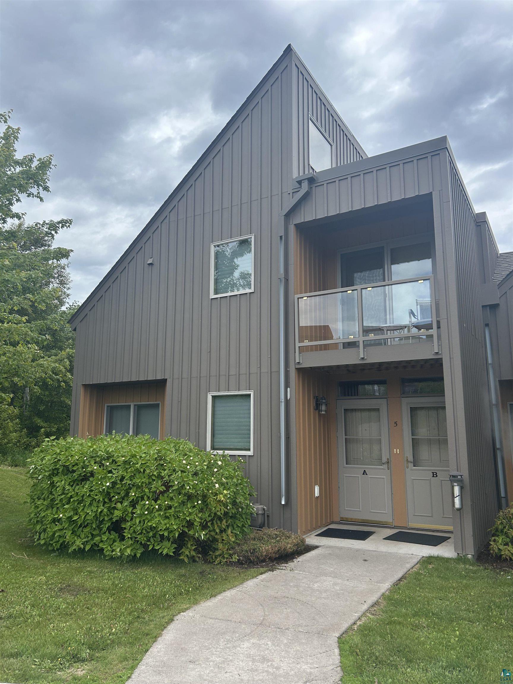 40 Surfside Drive, Unit 5D Tofte, MN 55615 - Photo 1 of 37 Modern architectural style featuring vertical panel siding, multiple windows, and a glass-paneled balcony