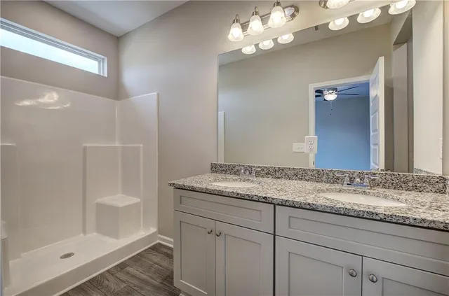 a bathroom with a granite countertop sink a mirror and shower