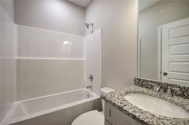 a bathroom with a granite countertop sink a toilet and bathtub