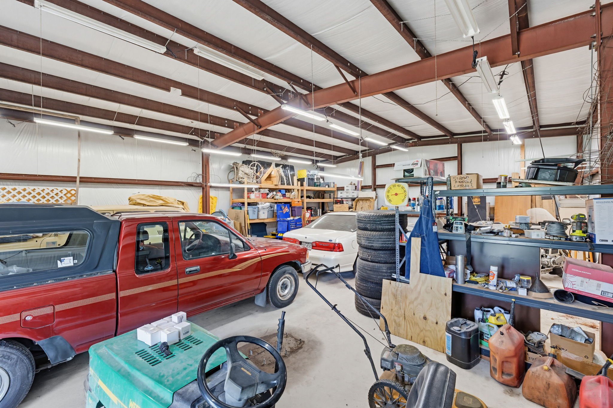 120 Rae Lane Jarrell, TX 76537 - Photo 14 of 40 Spacious metal building interior featuring exposed beam construction, white insulated walls, concrete flooring, and ample overhead lighting