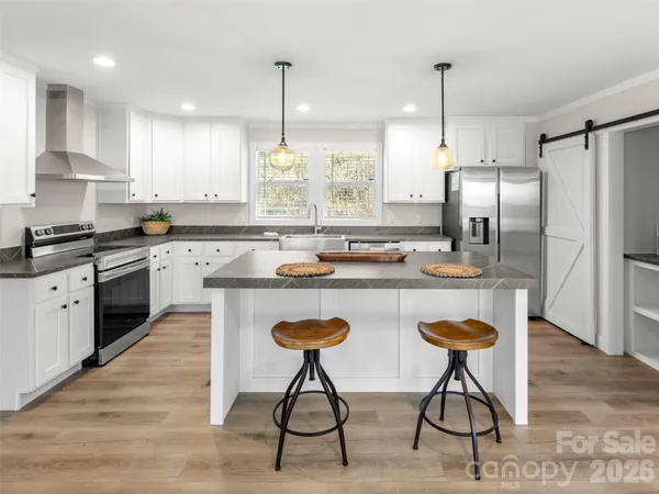 a kitchen with stainless steel appliances granite countertop a sink a stove a refrigerator and island with wooden floor